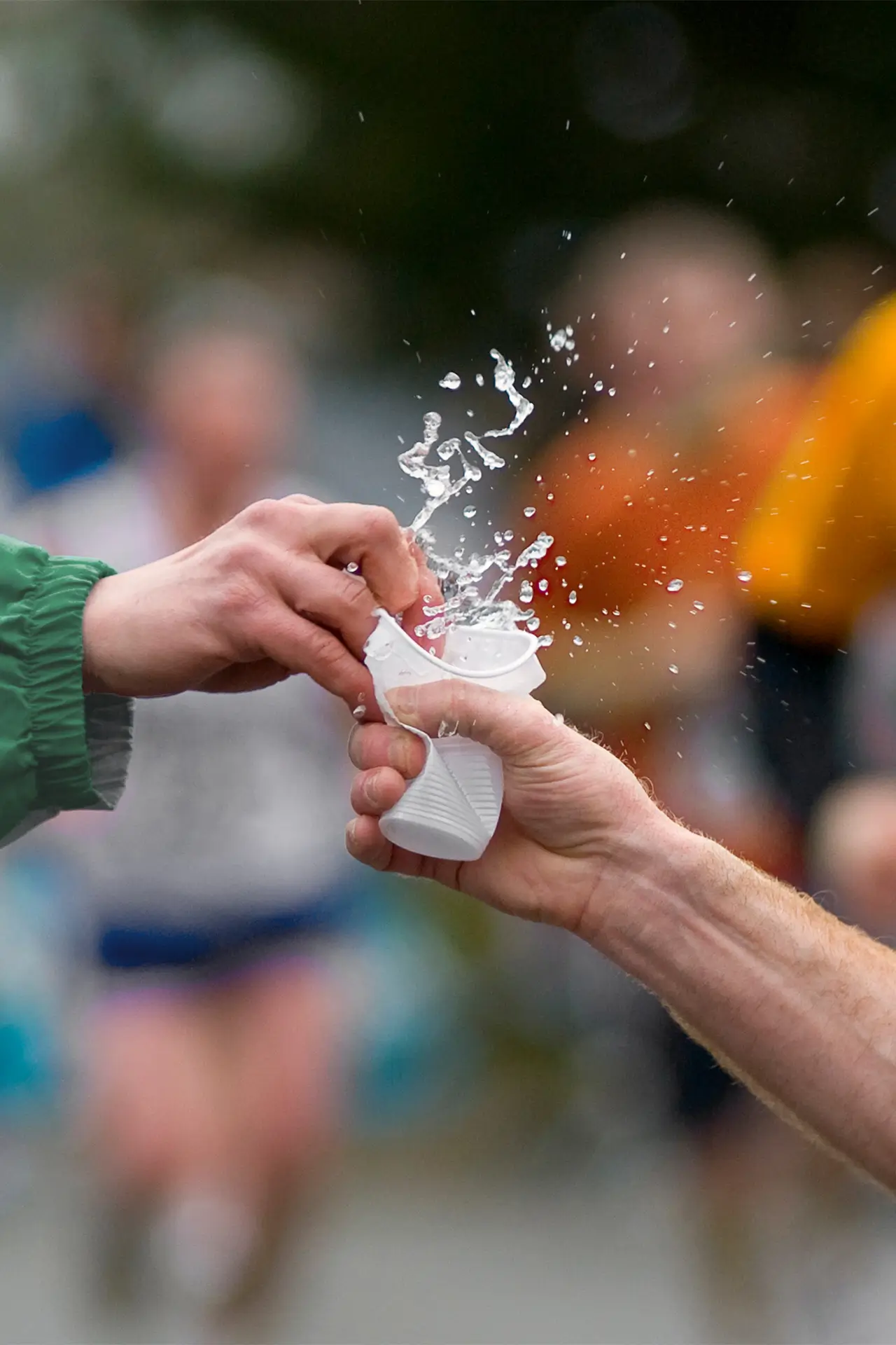 Helfer reicht Wasserbecher an Sportler