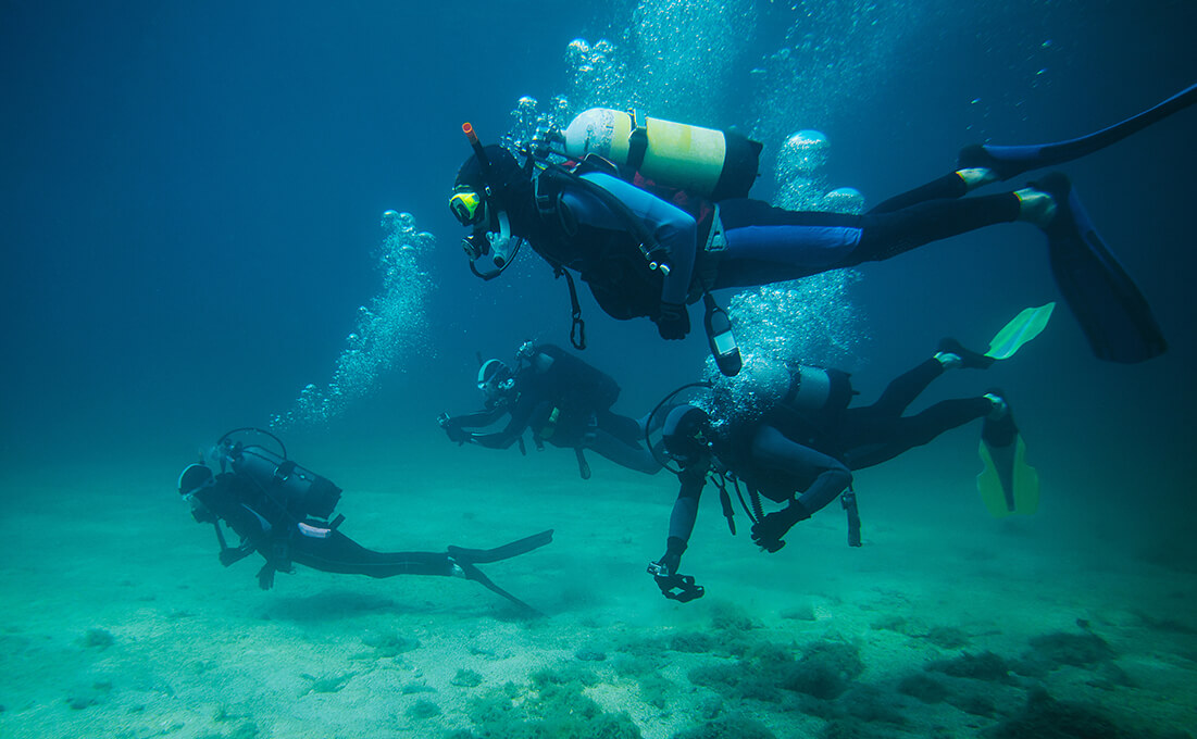 Gruppe von Tauchern übt gemeinsam einen Tauchgang unter Wasser